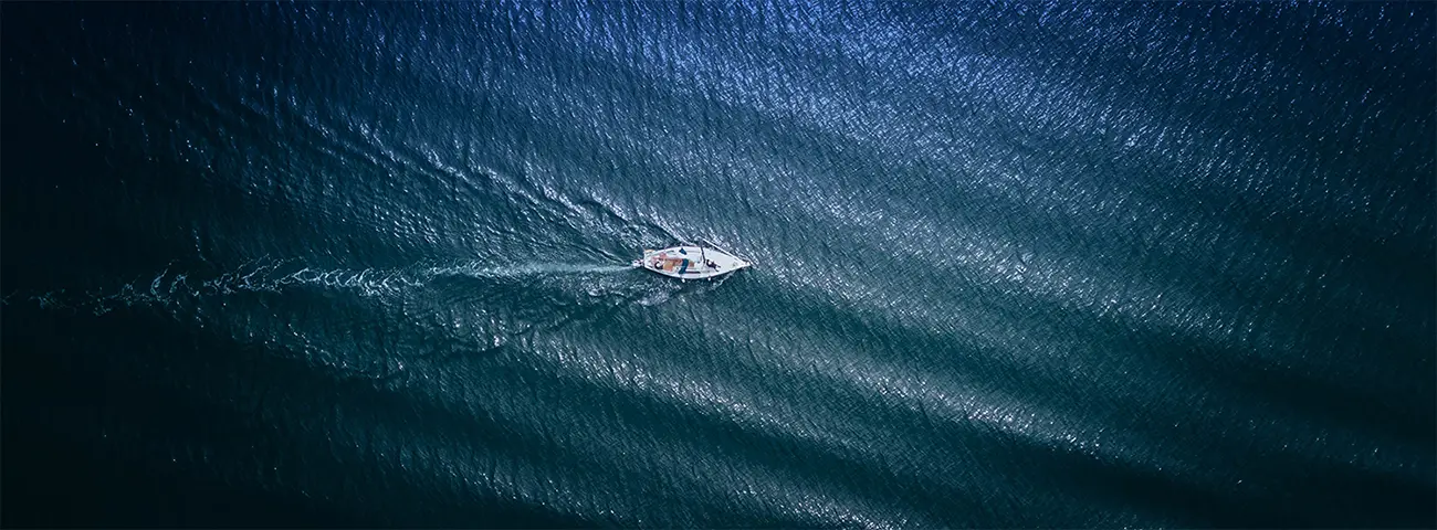 Overhead view of a sailboat sailing from left to right