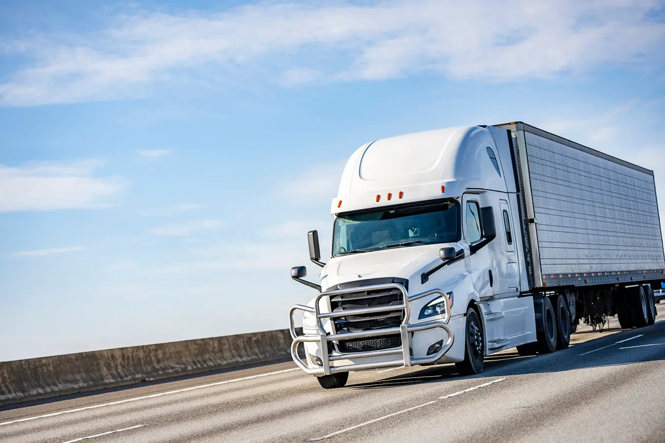 trucking-insurance-case-study-1 White semi truck pulling a white trailer on the freeway