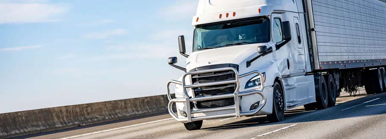 White semi truck pulling a white trailer on the freeway