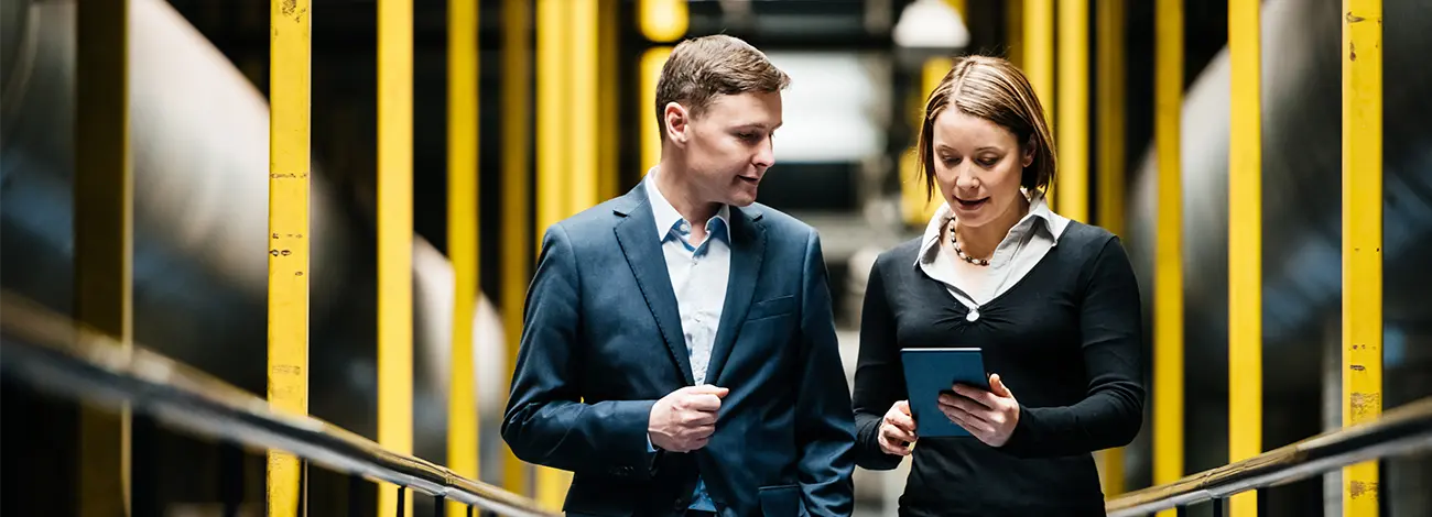 An insurance consultant walking with a tablet in her hand and showing the contents to a client