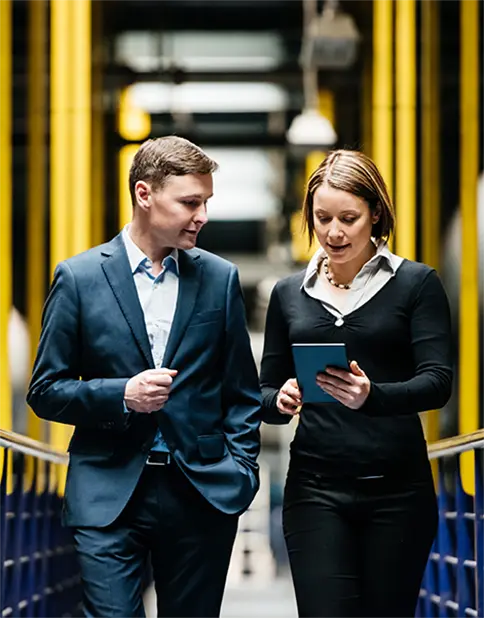 An insurance consultant walking with a tablet in her hand and showing the contents to a client