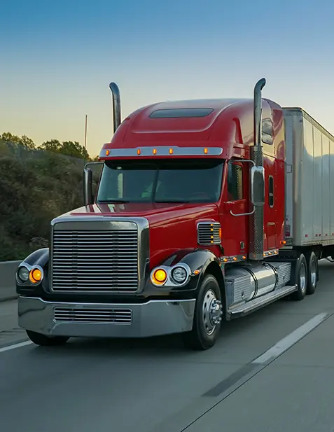 Red semi truck pulling a white trailer on the freeway